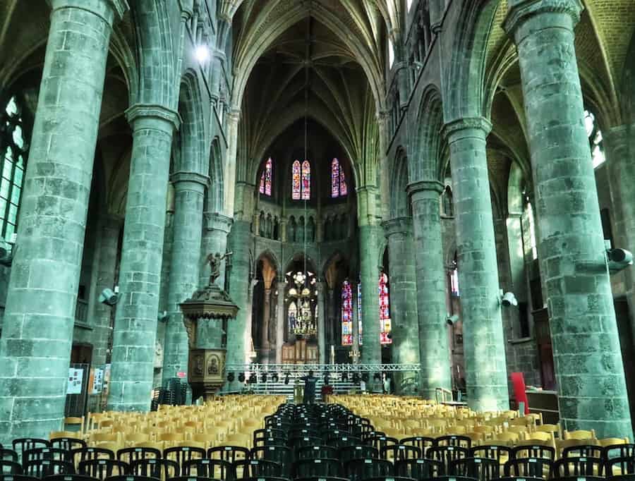 Interior of the Notre Dame de Dinant, Belgium showing empty seats between tall columns leading to the alter