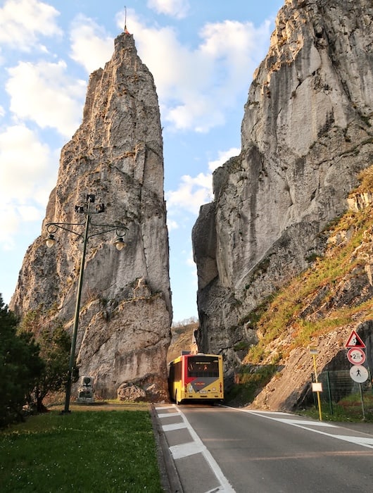 A bus passes through a tiny gap of a tall rock that is Rocher Bayard in Dinant. 