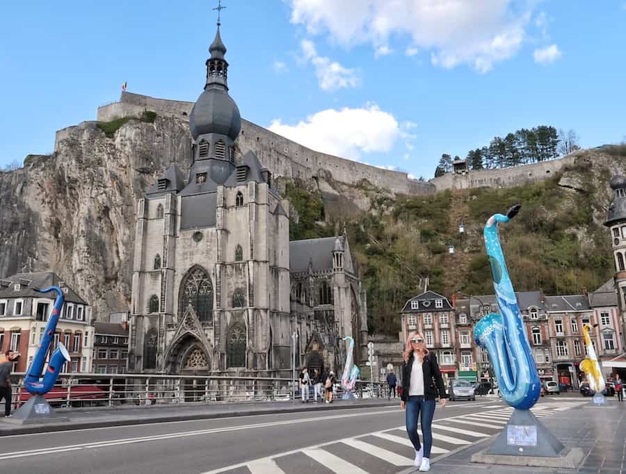 Zuzi walks across the Charles de Gaulle Bridge. There are colourful models of saxophones either side and the cathedral in the background