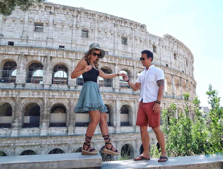 Feature image for 3 day Rome itinerary post. Jeff helps Zuzi to on a step by holding her hand. Colosseum in the background