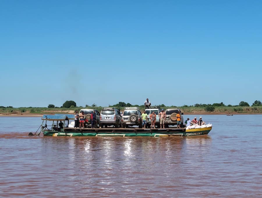 Image of a ferry on a river in Madagascar. There five vehicles on the boat