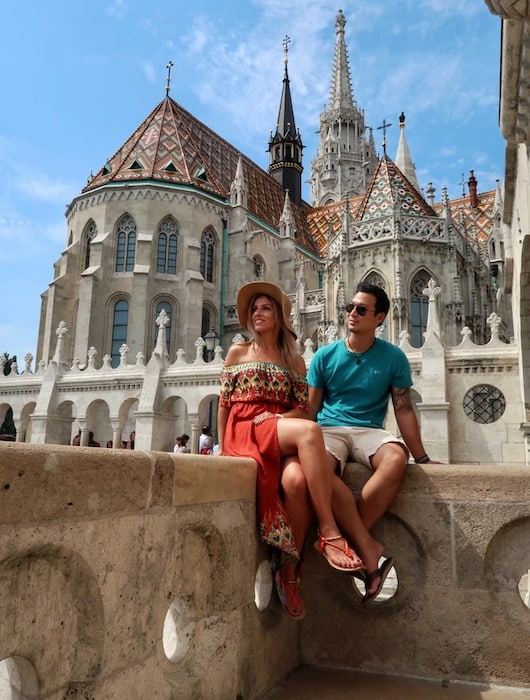 Jeff and Zuzi sit on a wall on the Fisherman's Bastion with the Matthias Church behind them