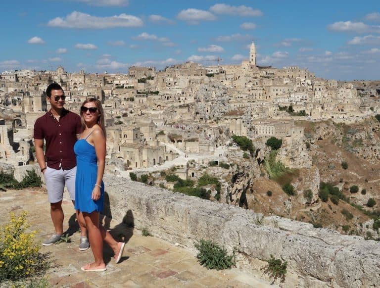 Feature image for Best Things To Do In Matera - couple standing in front of the cave city of Matera