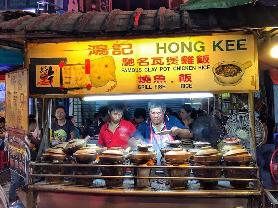 A man is serving food from his street food cart in Kuala Lumpur at night