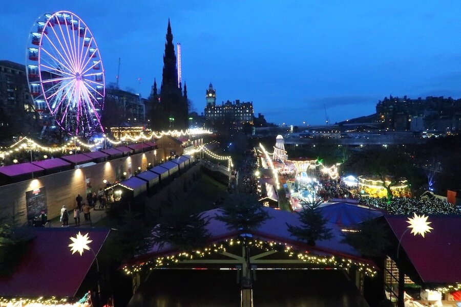 Image of Edinburgh Christmas market with the stalls, ferris wheel and church in view