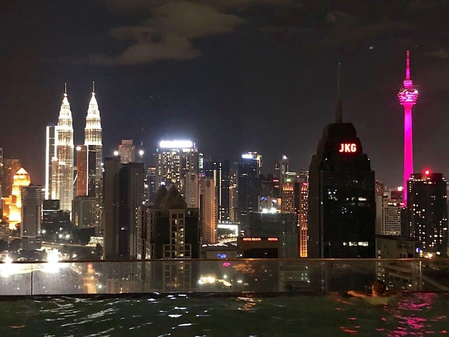 Image of a rooftop swimming pool with Kuala Lumpur city in the background at night