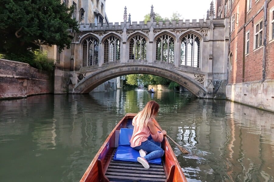 Zuzi sits on the front of the boat in Cambridge with the Bridge of Sighs in the background