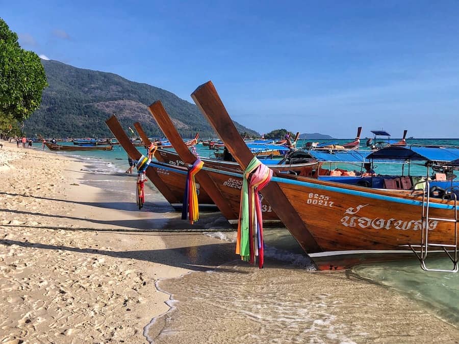 Image of many long-tail boats parked on the beach in Thailand