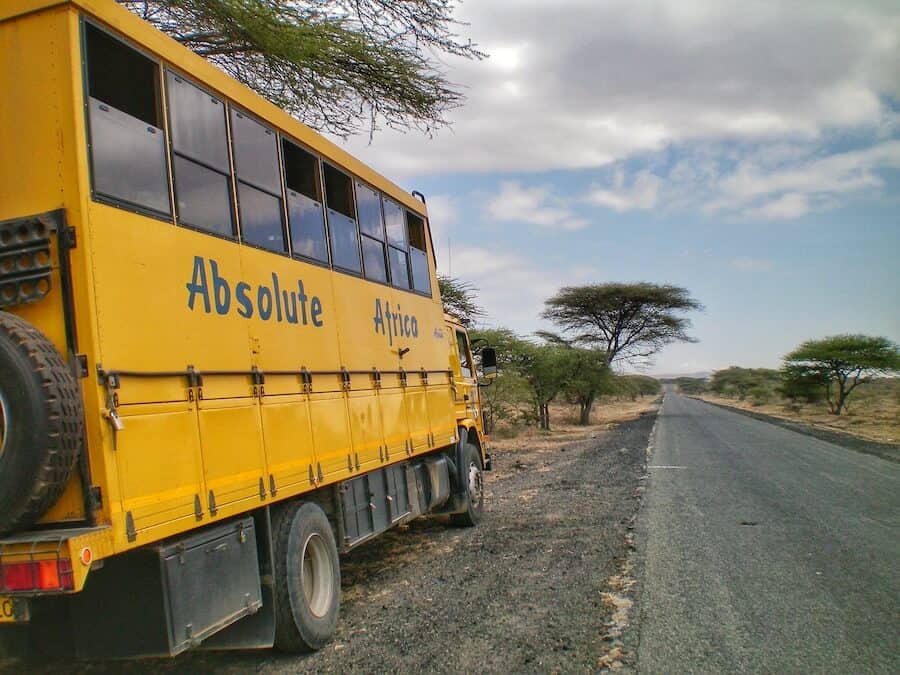 A big yellow truck with 'Absolute Africa' on the side is parked on a road in Kenya