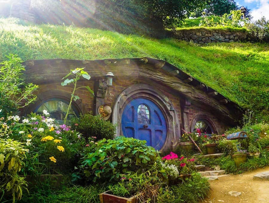 Cover image for Best Travel Movies featuring a house from Hobbiton. A small house with grass on the roof.