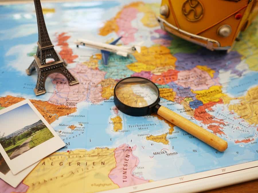 Image of a world map with a magnifying glass, photograph and other items on top