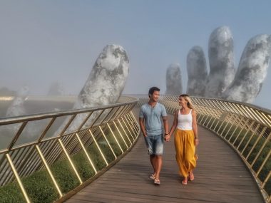 Cover image for Golden Bridge Vietnam post where Jeff and Zuzi are walking on the bridge with a giant stone hand in the background