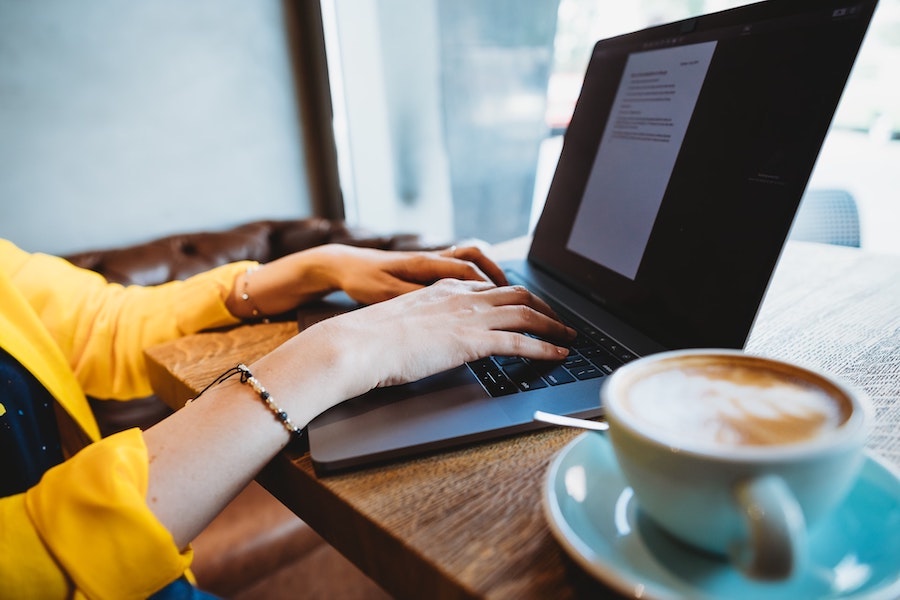 Image of someone working on their laptop in a cafe with a coffee in the foreground