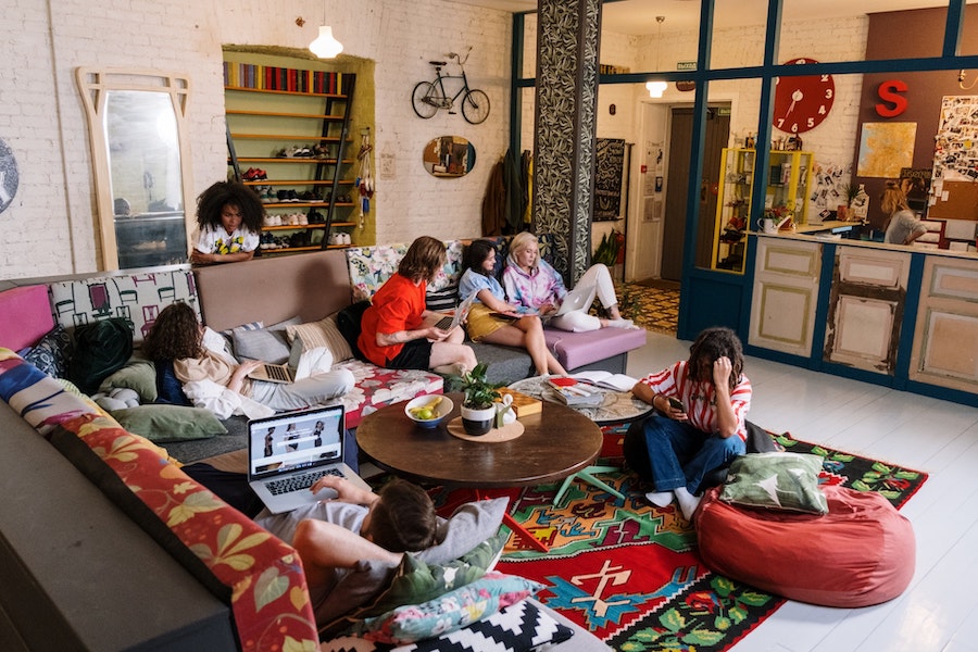 image of a hostel common room where several travellers are sitting in various seats around the room