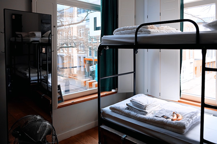 Image of a hostel dorm room with a bunk bed and window view