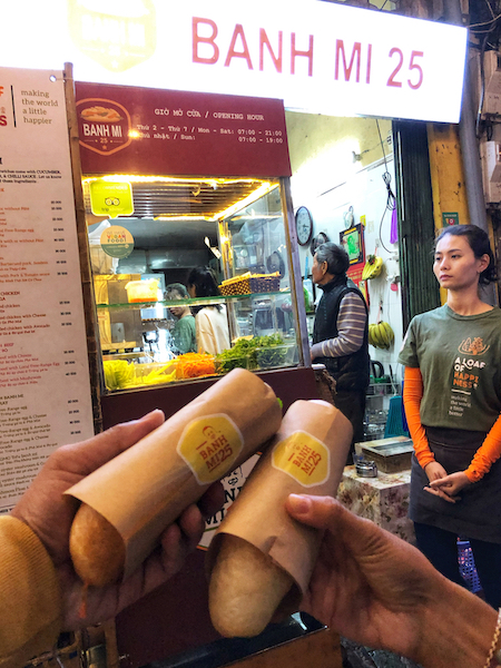 Image of a couple of banh mi baguettes outside a shop with the sign Banh Mi 25