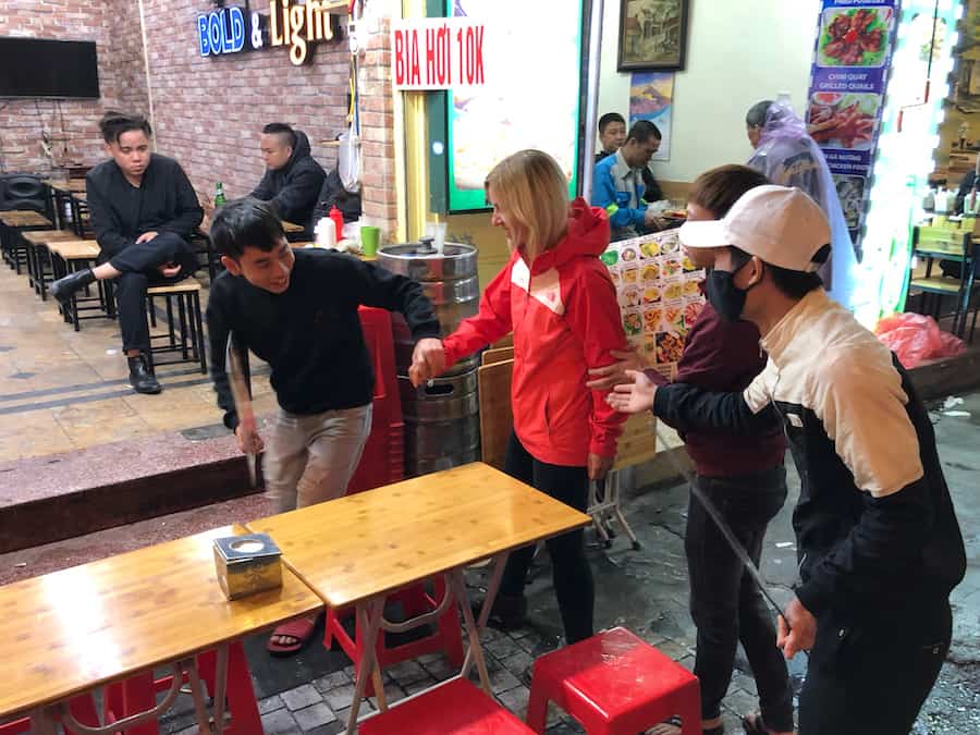 Zuzi, in the red coat, is being led to a seat by three Vietnamese teenagers.