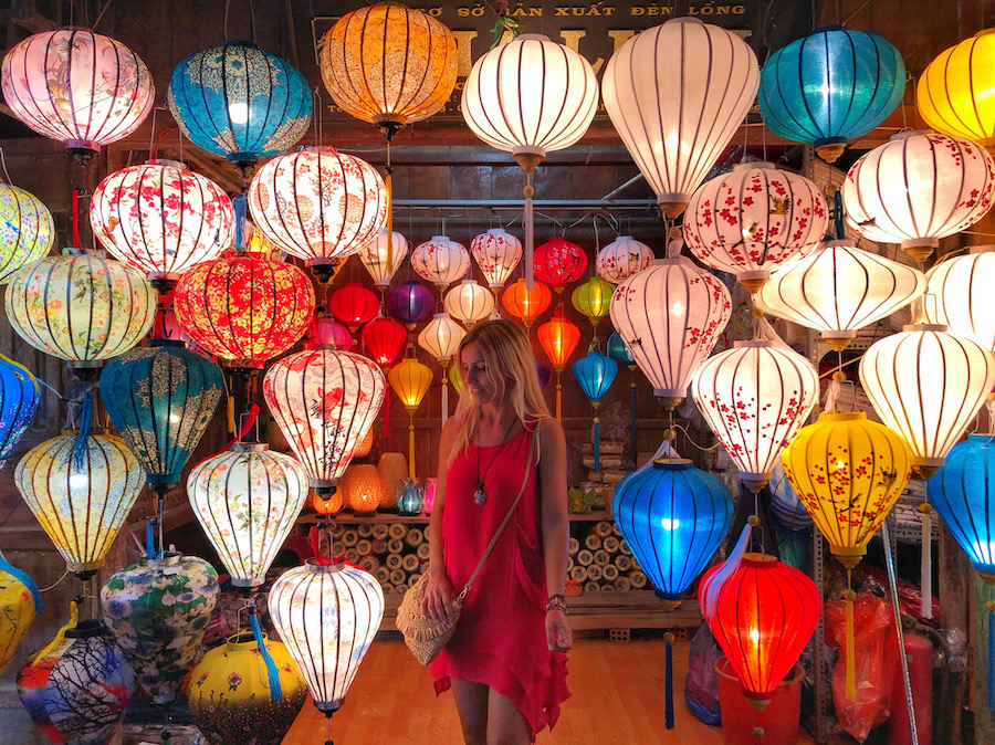 Zuzi, in a red dress, is in a lantern shop in Hoi An surrounded by many colourful lanterns