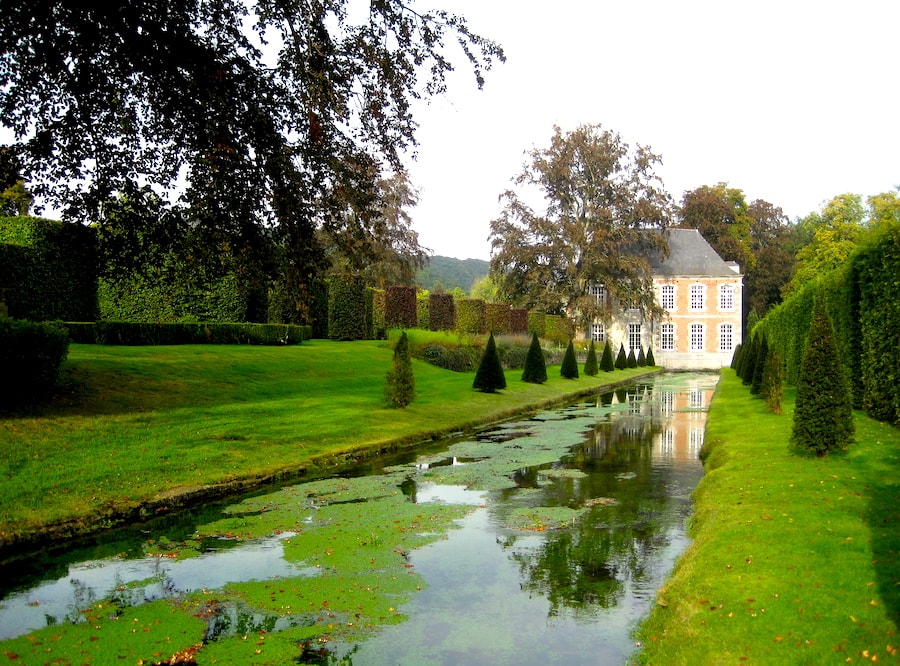 Image of Jardins d’Annevoie in Dinant, there is a small canal with a house in the distance