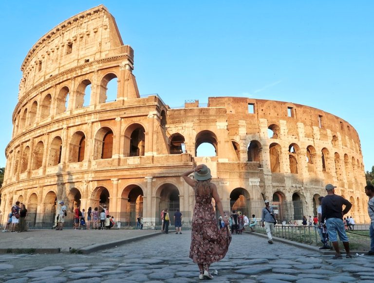 Title image for Italy Instagram Captions showing Zuzi in a hat standing in front of the Colosseum in Rome