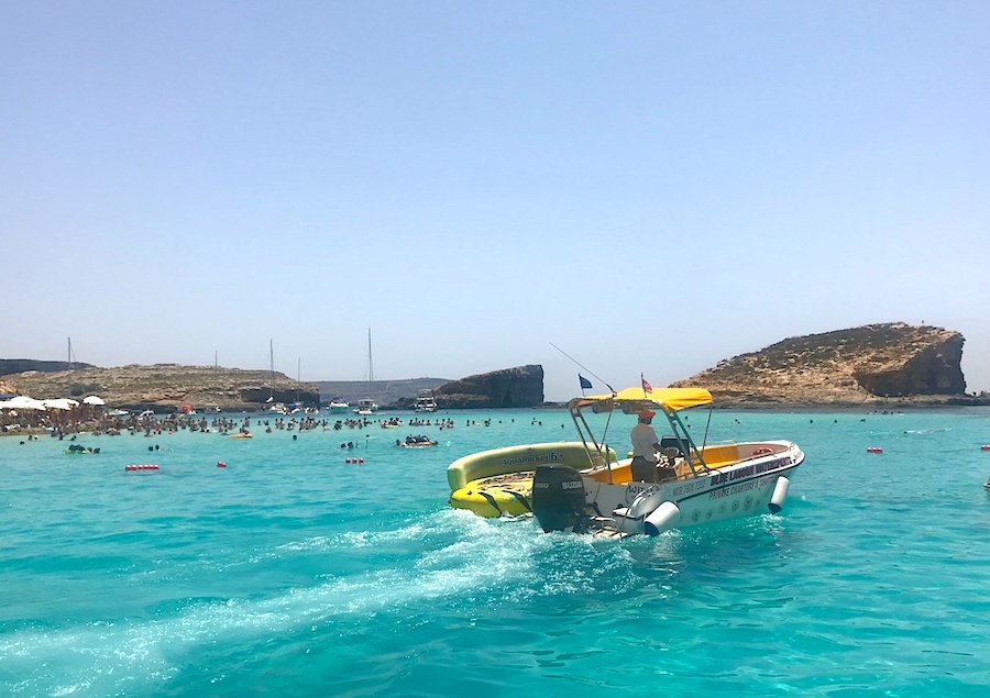 a speedboat cruises on turquoise sea at the Blue Lagoon, Malta