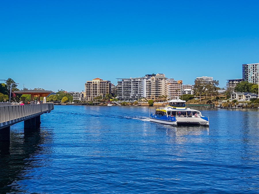 Brisbane CityCat ferry cruising along the river with city skyline in the background.