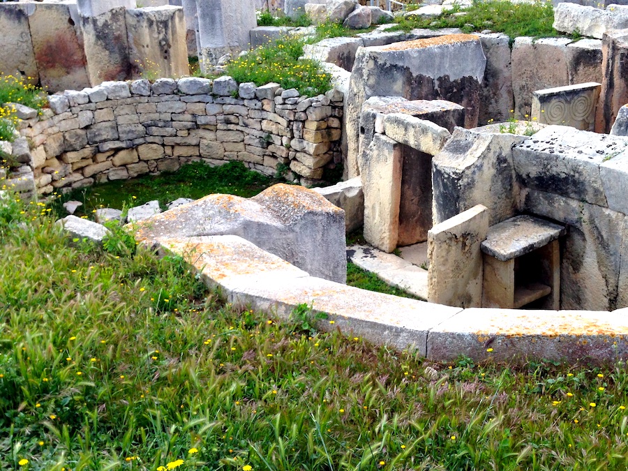 a temple entrance made from large blocks of stone with grass in the foreground