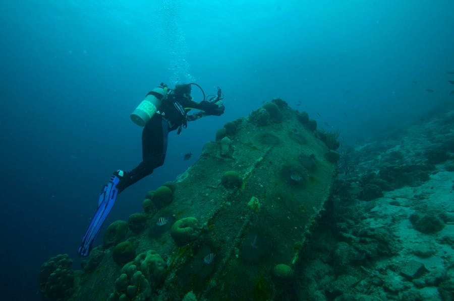 Scuba diver is under water taking photos of a wreck