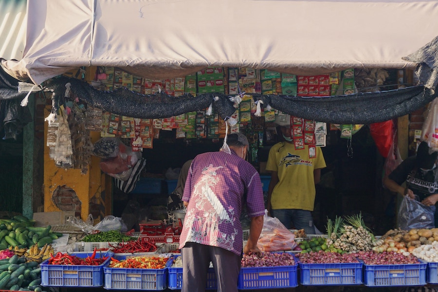 Local man in a purple shirt is buying produce at a local market.