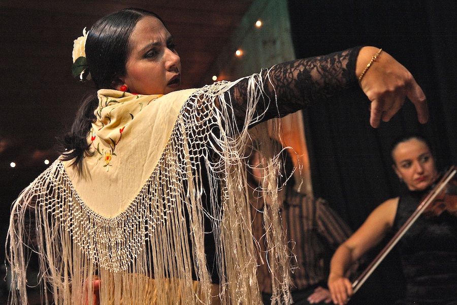 Woman performing flamenco with a violinist in the background