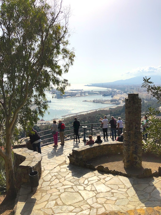 Tourists take in the view of Malaga Harbour from the Mirador del Gibralfaro viewpoint