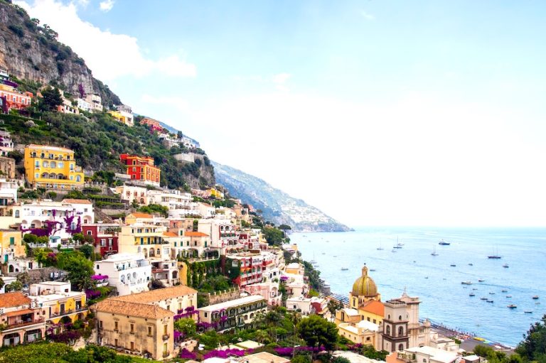 View of Positano for the blog post 'Sorrento Vs Positano' showing colourful houses on the mountainside and the sea on the right.