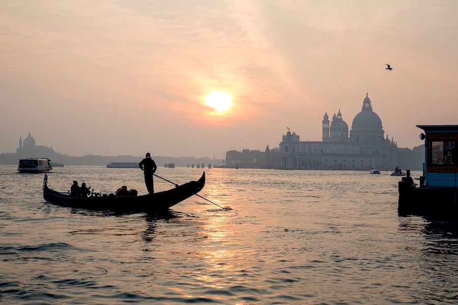 silhouette of a man on a gondola in the canals of Venice