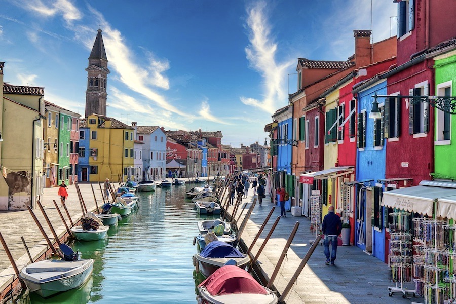 A boat filled canal in Burano showing colourful houses either side