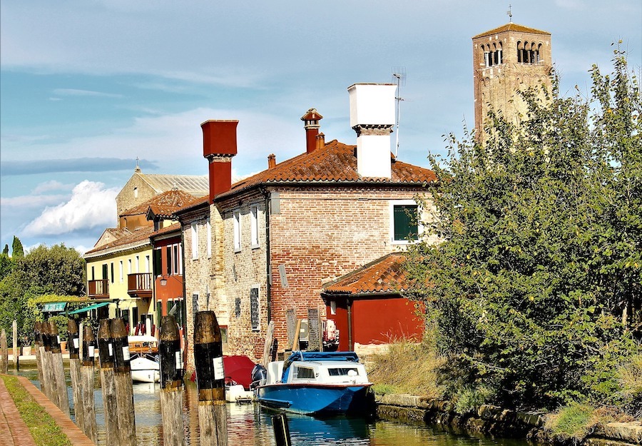 An old looking water way town of Torcello near Venice. A boat in sitting on the canal with an old brick building on the side