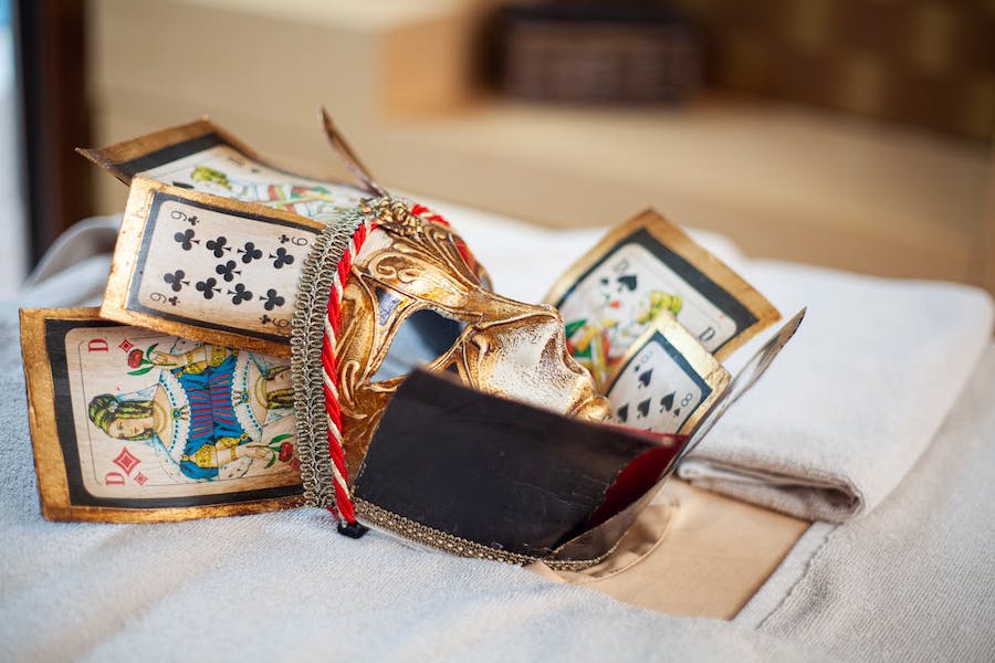 A mask used for the Venice carnival with a gold face and playing cards for a crown.