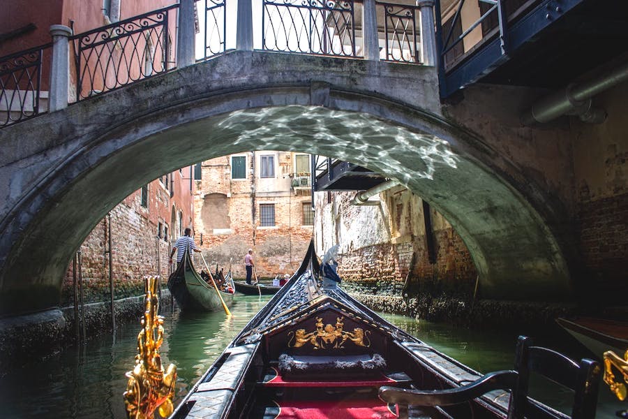 View from a gondola in Venice passing a low bridge along the canal