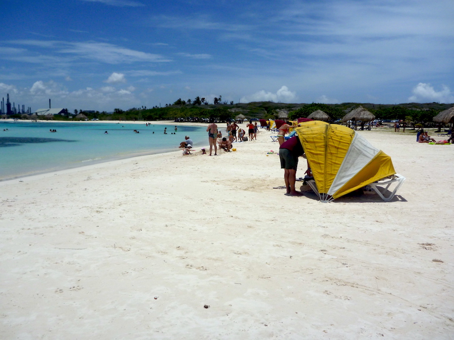 People at Baby Beach Aruba on the sand with a yellow cabana in the foreground