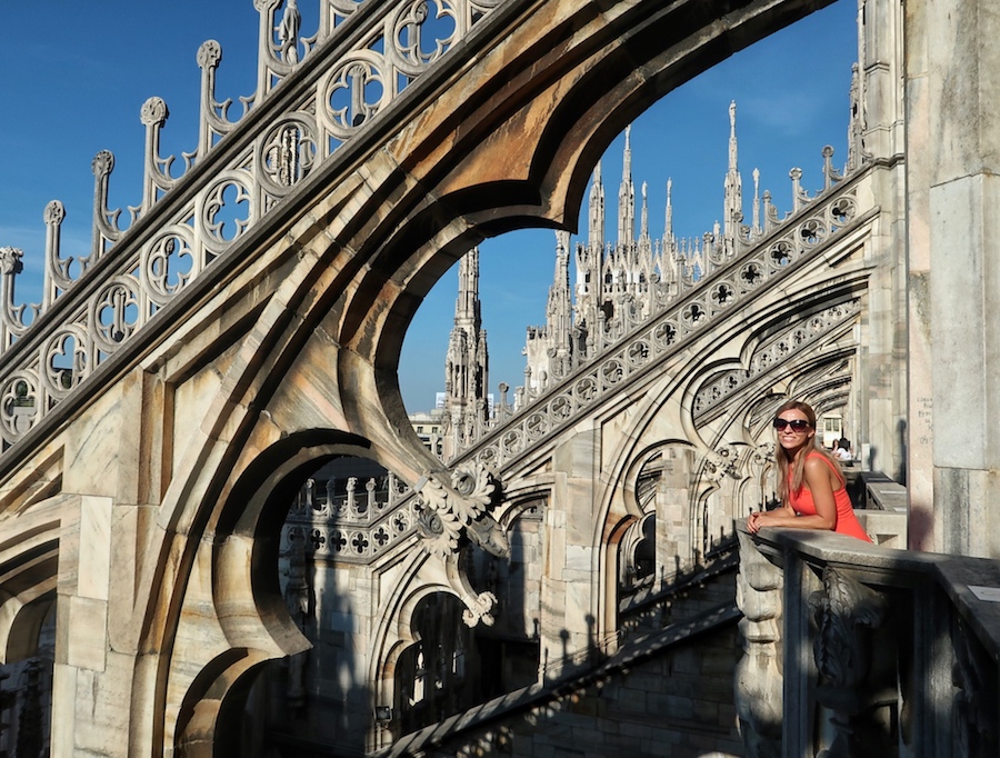 Zuzi stands on the Milan Duomo rooftop with Gothic decorated beams