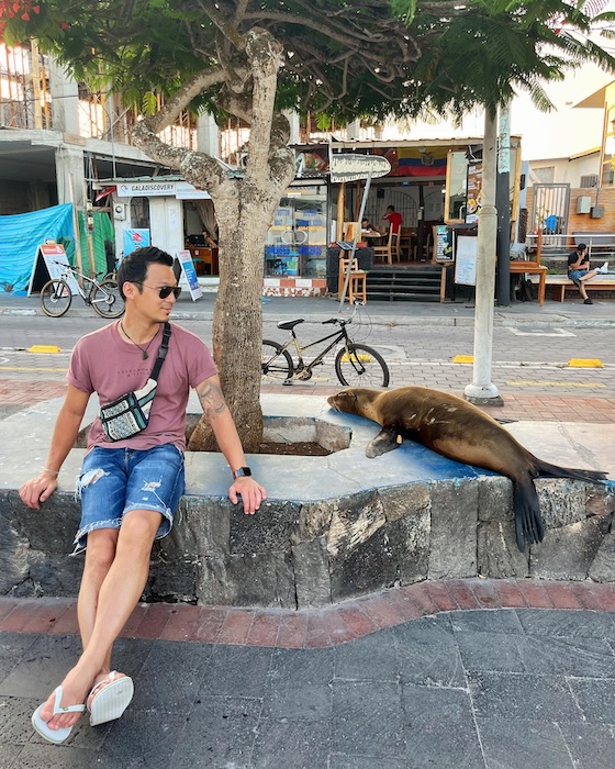 Jeff sits next to a sea lion in the street in the Galapagos