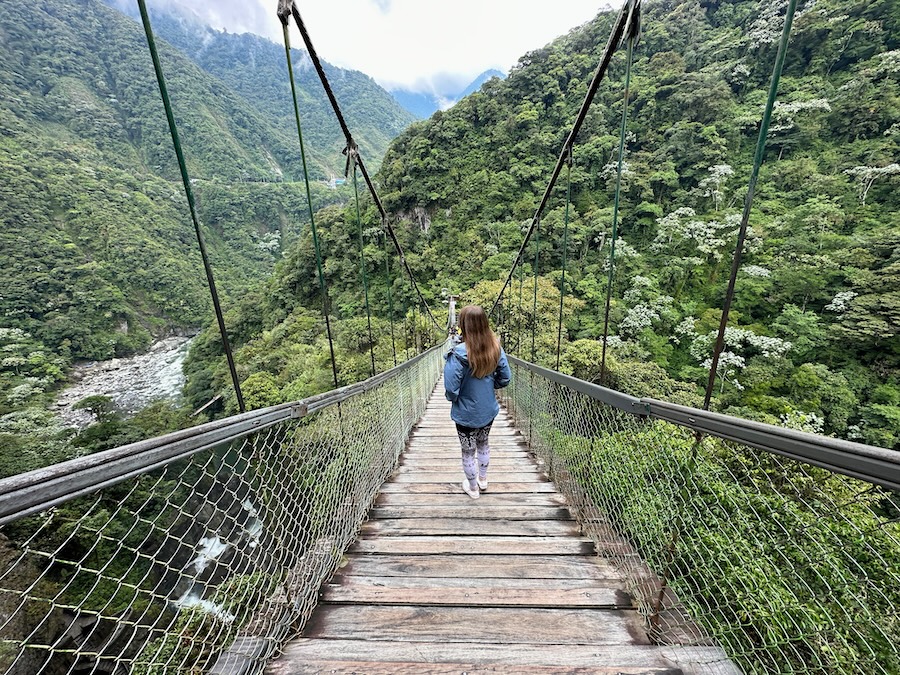 Woman walking across suspension bridge near Pailón del Diablo in Ecuador.