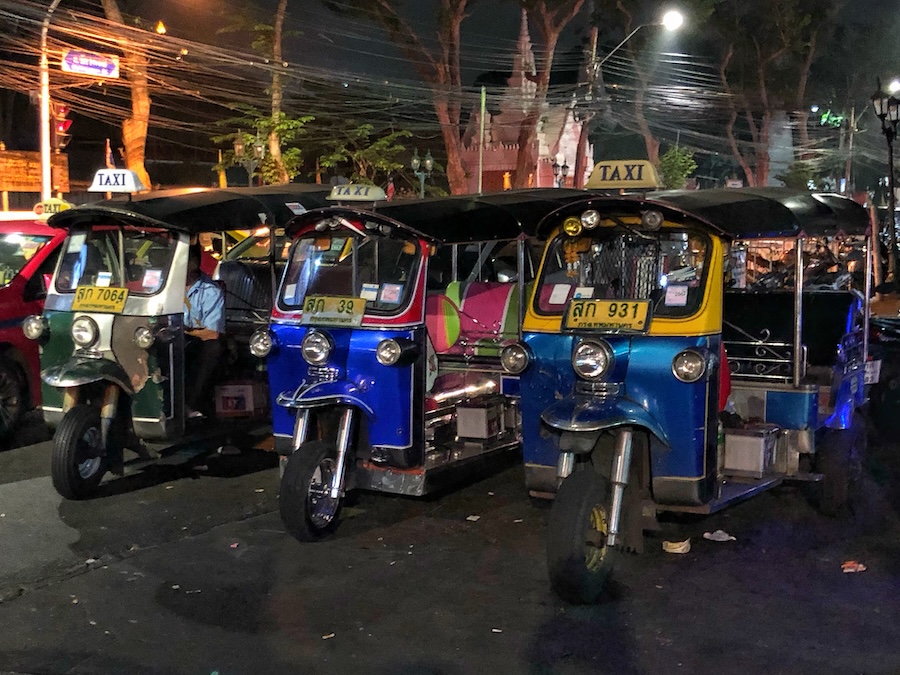 Three tuk-tuks in Bangkok wait for customers
