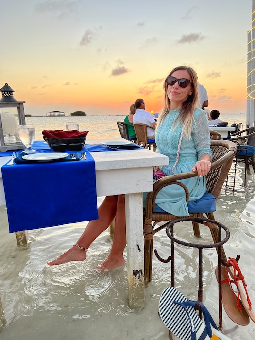 Guest seated at a Flying Fishbone water table with feet in the shallow sea