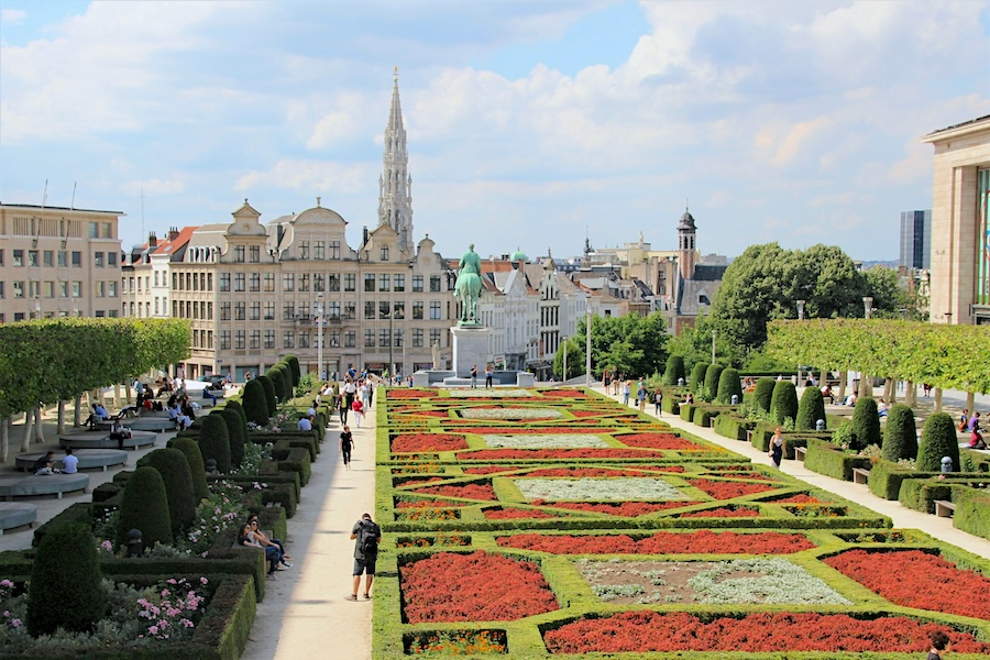 Colourful geometric flower beds and manicured gardens at Mont des Arts in Brussels, overlooking historic buildings and the Town Hall spire.